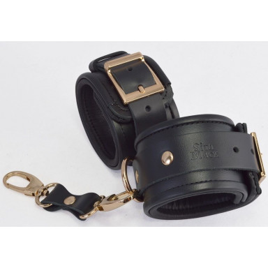Черные кожаные наручники с золотистыми пряжками и карабином, фото